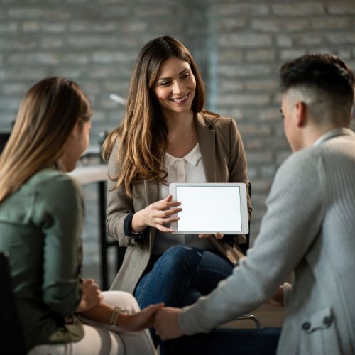 Three people talking over a tablet in a relaxed meeting