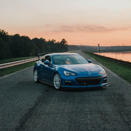 A blue sports car on an open road at sunset