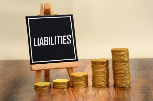 A liabilities sign beside stacks of coins