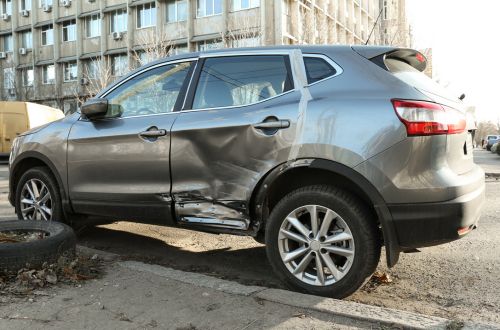 A gray SUV with collision damage on its side